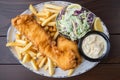 overhead shot of a plate of freshly made fish and chips topped with a sprinkle of salt and a side of creamy coleslaw