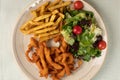 Overhead shot of a plate with fries, salad, and deep-fried seafood slices Royalty Free Stock Photo