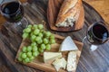 Overhead shot of red wine, cheese, grapes and bread on wood platter Royalty Free Stock Photo