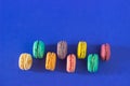 Overhead shot of rows of colorful macarons on a blue background