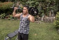 Overhead shot of a short but fit asian guy doing standing dumbbell presses. Shoulder workout.