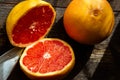Overhead shot of sliced and whole fresh, juicy seasonal grapefruits and a knife on a wooden table