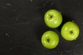 Overhead shot - three green apples on black board, space for text on left side Royalty Free Stock Photo