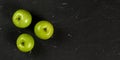 Overhead shot, three green apples on black marble like board, wide banner with space for text right