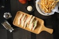 Overhead shot of toats on a wooden tray near sauce and french fries