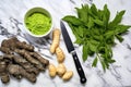 overhead shot of wasabi roots, paste, and a knife on a marble countertop