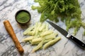 overhead shot of wasabi roots, paste, and a knife on a marble countertop