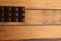 Overhead shot of a whole dark chocolate bar on a wooden table under the lights