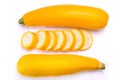 Overhead shot of whole yellow zucchinis and slices on a white background