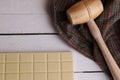 Overhead shot of a wooden small mallet near a bar of white chocolate