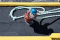 Maritime Work Ethic: Overhead Shot of a Worker in Reflective Vest and Blue Helmet Pulling a Thick Rope on a Ship Royalty Free Stock Photo