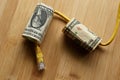 Overhead shot of a yellow cable going through dollar bills on a wooden surface