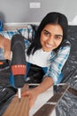 Overhead shot of young Indian woman drilling into wood during home renovation