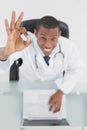 Overhead of a smiling doctor with laptop gesturing okay sign