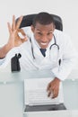 Overhead of a smiling male doctor with laptop gesturing okay sign