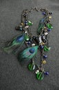Overhead vertical shot of a necklace with peacock feathers on a black surface Royalty Free Stock Photo