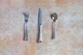 Overhead view of an antique silver cutlery consisting of a fork, spoon, and knife on an abstract background. Royalty Free Stock Photo