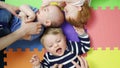 Overhead view of babies lying on mat at nursery playgroup being tickled