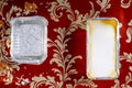 Overhead Lasagna and Empty Foil Tray on Red Floral Background
