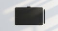 Overhead view of black graphics tablet and stylus on white surface Royalty Free Stock Photo