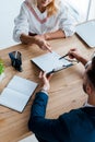 View of blonde employee pointing with finger at clipboard near recruiter