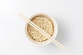 Overhead view of bowl with raw instant Asian egg noodles and chopsticks on white background