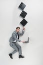 overhead view of businessman with stack of folders on one finger using laptop