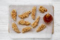 Overhead view chicken strips with sauce on bamboo board over white wooden background. Royalty Free Stock Photo