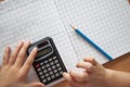 Overhead view of a child using a calculator to solve maths questions Royalty Free Stock Photo