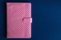 Overhead View of Closed Pink Perforated Notebook on Dark Blue Background Royalty Free Stock Photo