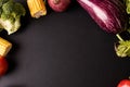 Overhead view of corn, onion, broccoli and eggplant on black background with copy space