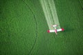 A crop duster spraying a green farm field. Royalty Free Stock Photo