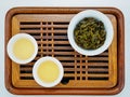 Overhead view of cups of green oolong tea and tea leaves on a wooden tray Royalty Free Stock Photo