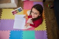 Overhead view of a cute little child girl smiling looking at camera, drawing with pastel pencils, sitting on a colorful Royalty Free Stock Photo