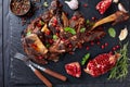 Overhead view of delicious roast leg of lamb served with pomegranate seeds, mint leaves, spices and rosemary on a black slate Royalty Free Stock Photo