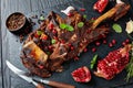 Overhead view of delicious roast tender leg of lamb served with pomegranate seeds, mint leaves, spices and rosemary on a black Royalty Free Stock Photo