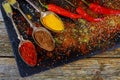 Overhead view depicting cooking with spices in a rustic kitchen with bowls of colourful ground spice and scattered powder on an ol Royalty Free Stock Photo