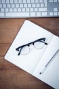 Overhead view of diary with pen and eyeglasses by keyboard Royalty Free Stock Photo