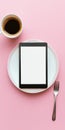 Overhead view of digital tablet on plate with coffee and fork on pink background Royalty Free Stock Photo