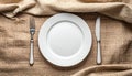 Overhead View of Empty White Plate with Fork and Knife on Textured Brown Fabric empty plate Royalty Free Stock Photo