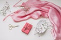 Overhead view of essential beauty items, top view of pink silk fabric, natural soap, flowers and decorative scissors Royalty Free Stock Photo