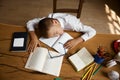 Overhead view on exhausted little schoolboy sleeping on desk table Royalty Free Stock Photo