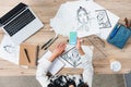 overhead view of female designer using smartphone with twitter application on screen at working table