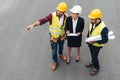 overhead view of female engineer and male workers with clipboard and blueprints pointing