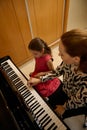 Overhead view of a female pianist musician holding the hands of a little child girl, showing the true position of finger