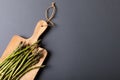 Overhead view of fresh asparagus on wooden cutting board by copy space against gray background Royalty Free Stock Photo