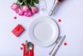 Overhead view of fresh pink roses and place setting with gift over white background, copy space Royalty Free Stock Photo