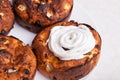 An overhead view of freshly baked brown buns with embossed white icing on one of them on a plate in front of the table -