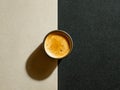Overhead view of a freshly brewed coffee cup casting a shadow across a textured surface split into light and dark contrasting Royalty Free Stock Photo