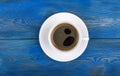 Overhead view of a freshly brewed mug of espresso coffee on blue rustic wooden background with woodgrain texture. Coffee break